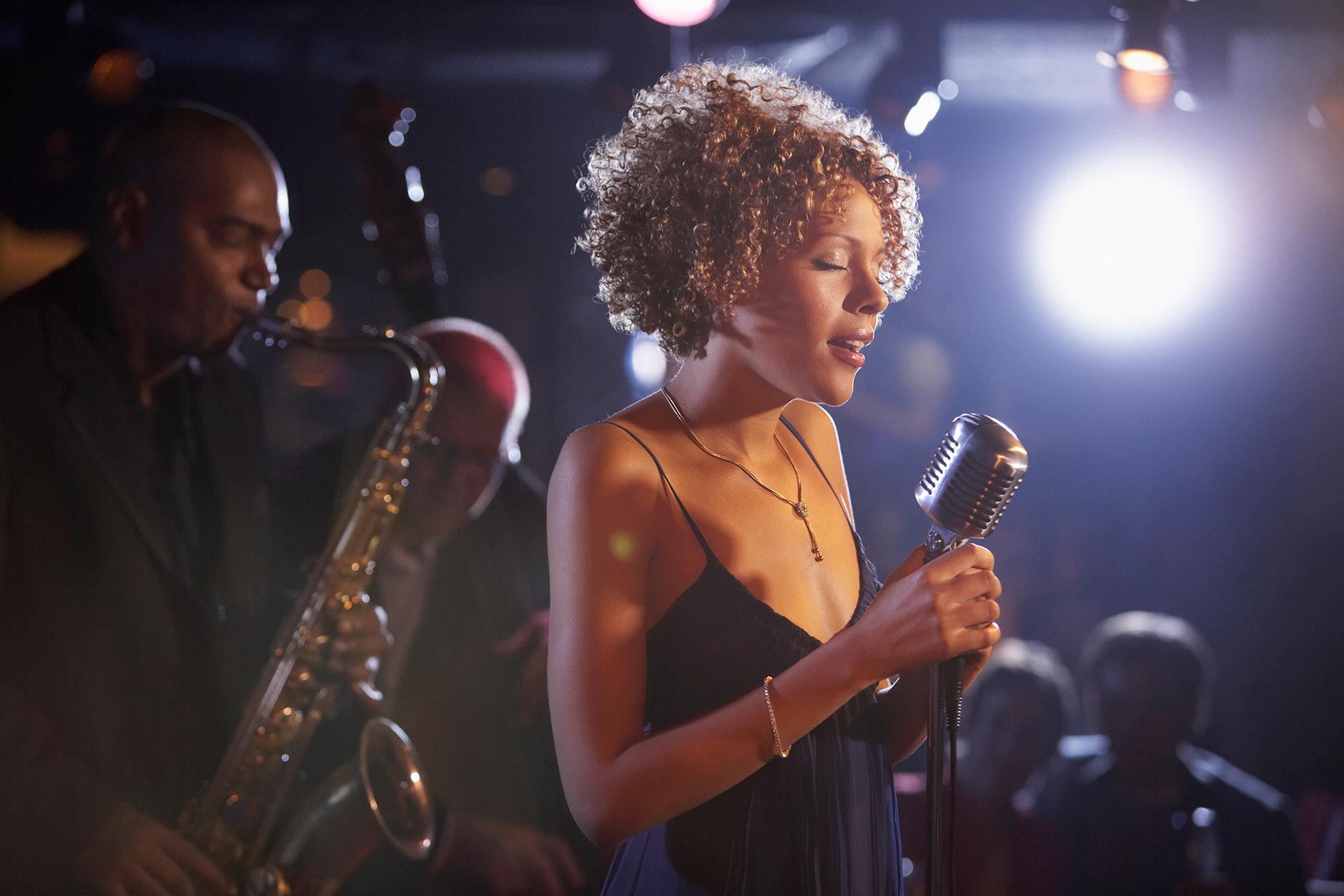 A woman singing with a man playing the saxophone
