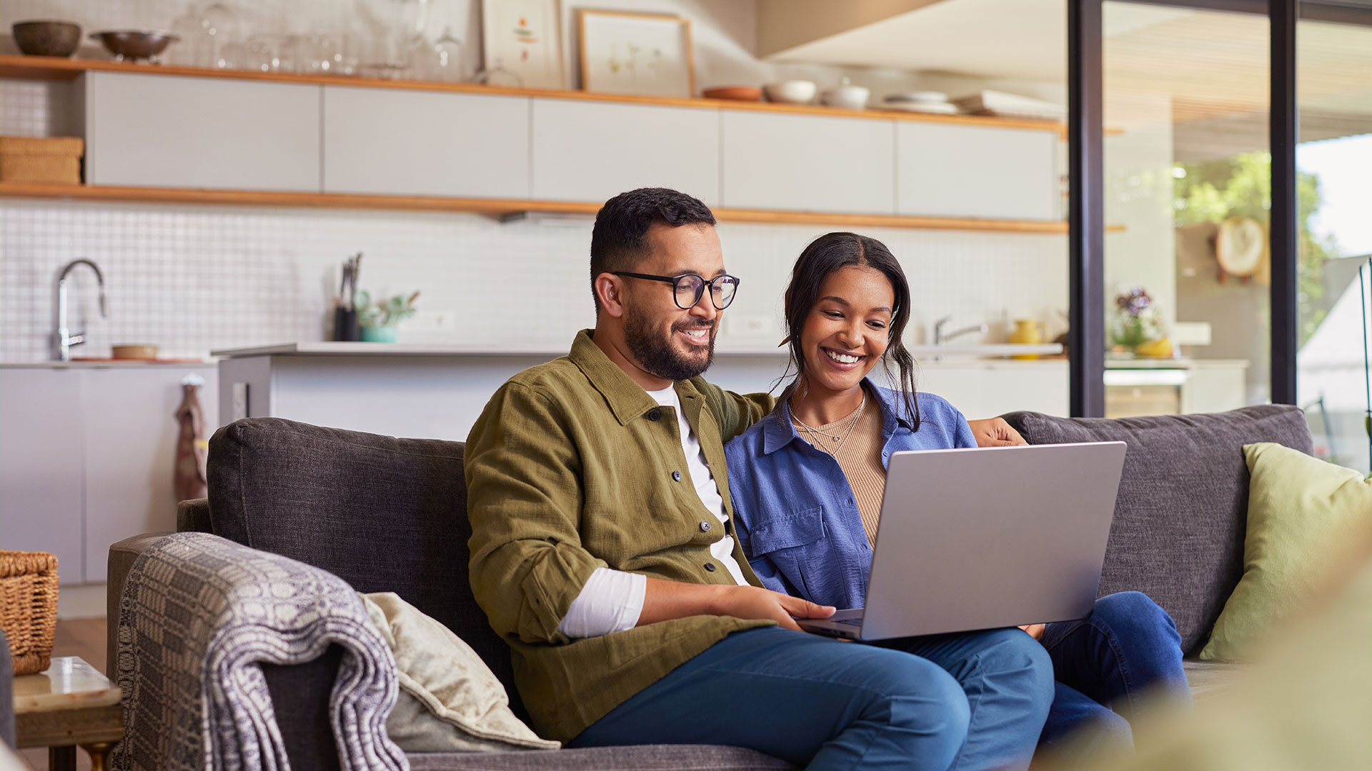 A couple sitting on a couch using a laptop